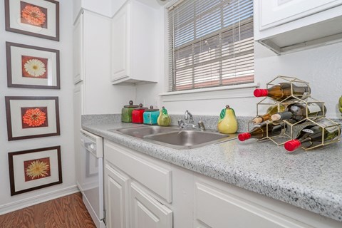 Furnished model apartment kitchen with double basin sink and white cabinets at Magnolia apartments in Shreveport, LA